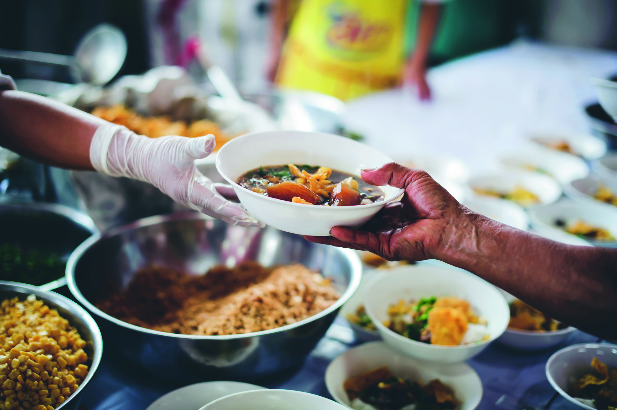 Volunteers scooping the food to share with the needy : concept o
